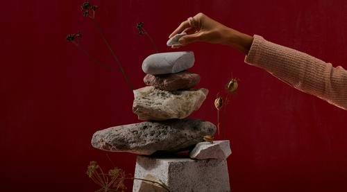 Une pile de pierres avec une main plaçant une pierre plus petite au-dessus.